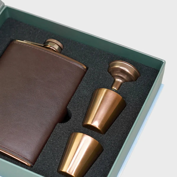 Brown leather flask and two bronze cups in a green box.
